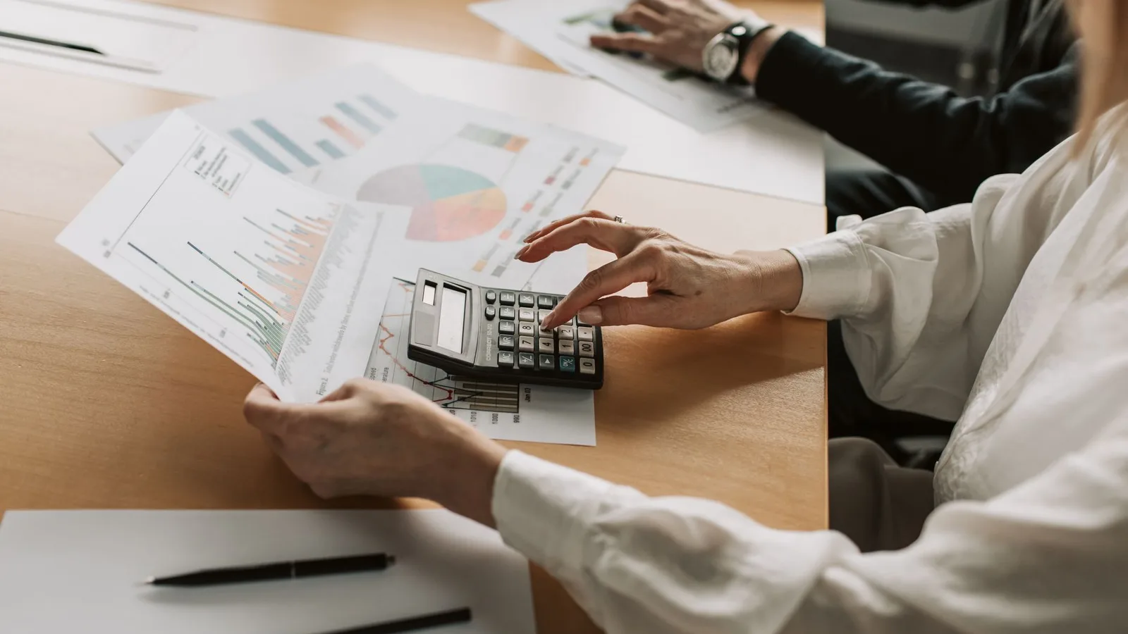 Profesionales analizando tendencias financieras con calculadora y gráficos